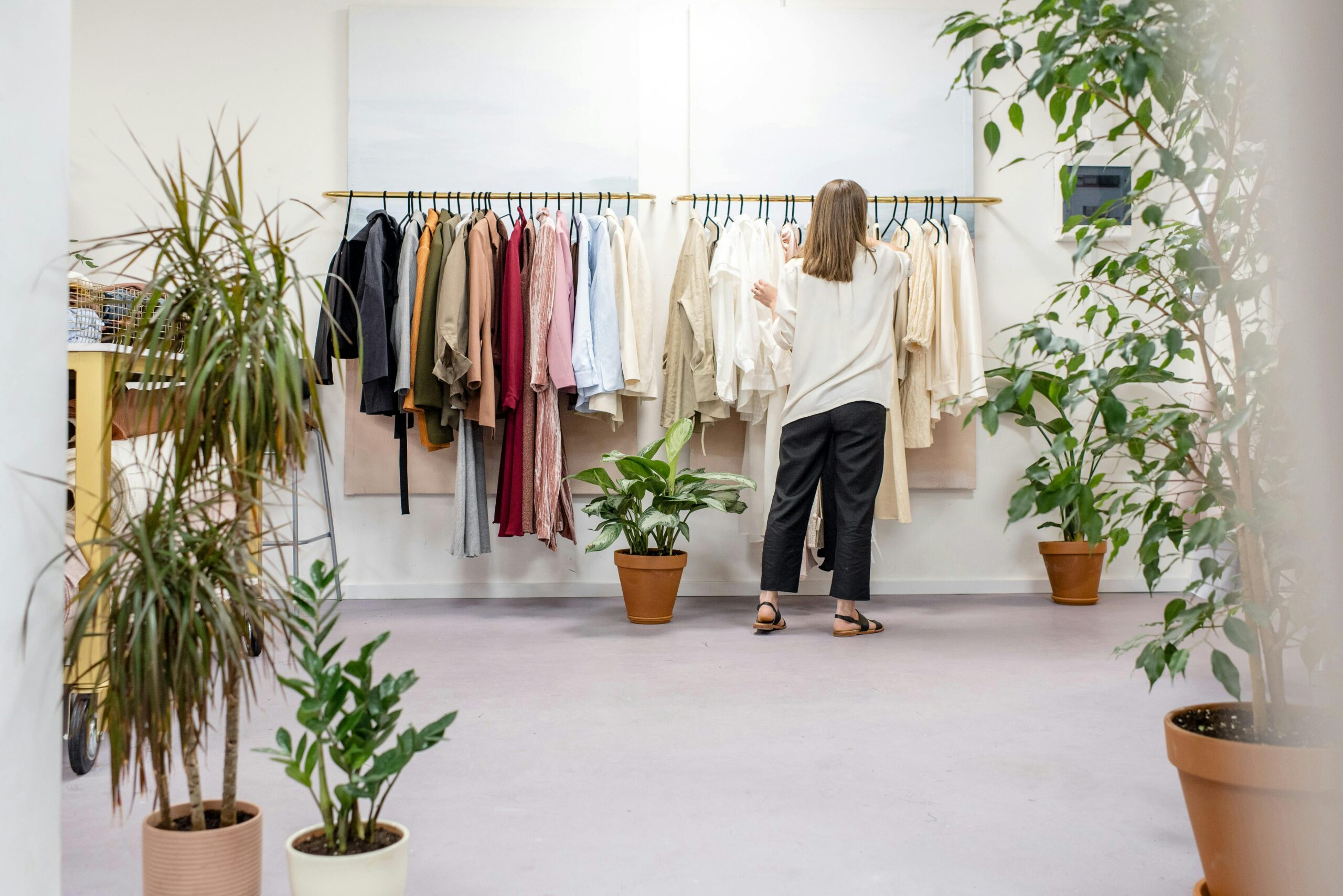 Customer browsing through clothing racks in a modern retail store, enhanced by digital human technology and ai-powered self-service kiosks for an improved shopping experience